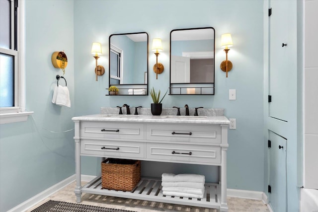 full bath with a sink, baseboards, and double vanity