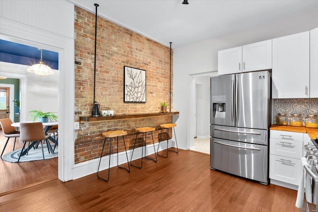 kitchen with butcher block counters, stainless steel appliances, wood finished floors, and white cabinetry