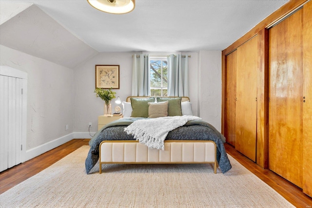 bedroom with baseboards, wood finished floors, and lofted ceiling