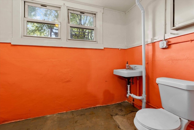 half bath with a sink, concrete floors, a wealth of natural light, and toilet