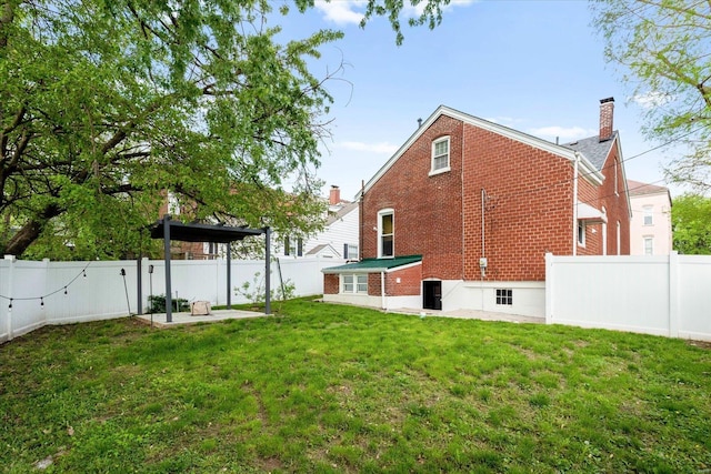 back of property featuring a yard, brick siding, a fenced backyard, and a patio area