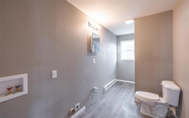 bathroom featuring a baseboard heating unit, toilet, baseboards, and wood finished floors