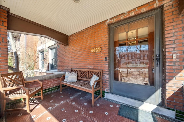 property entrance with a porch and brick siding