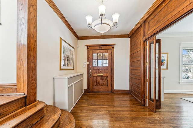 foyer featuring dark wood-type flooring, a notable chandelier, crown molding, and baseboards