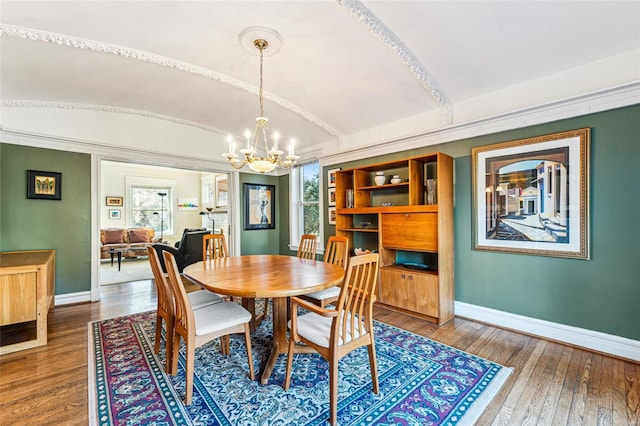 dining area featuring wood-type flooring, vaulted ceiling, baseboards, and an inviting chandelier