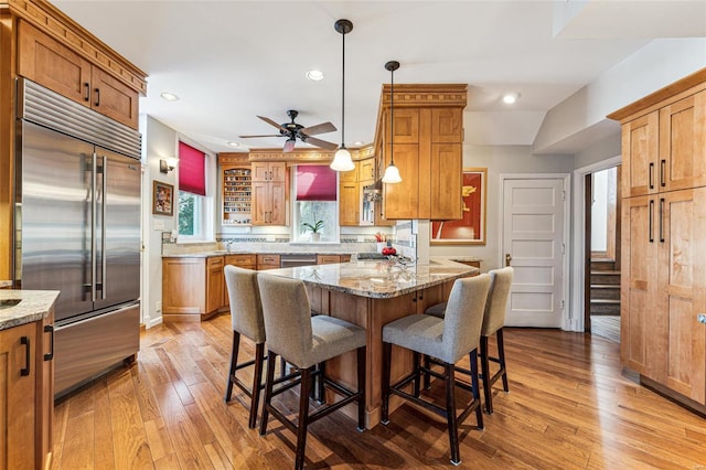 kitchen featuring appliances with stainless steel finishes, a breakfast bar, brown cabinets, and light wood-style flooring