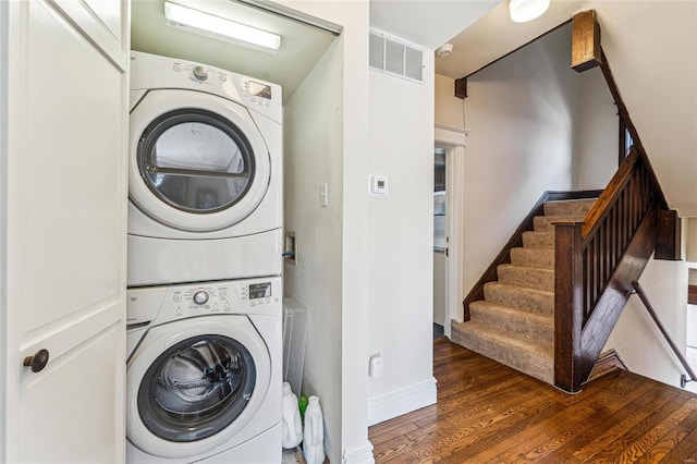 laundry area featuring laundry area, wood finished floors, visible vents, baseboards, and stacked washer / drying machine