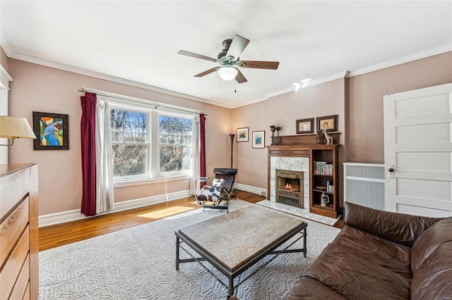 living area with wood finished floors, crown molding, baseboards, and a premium fireplace