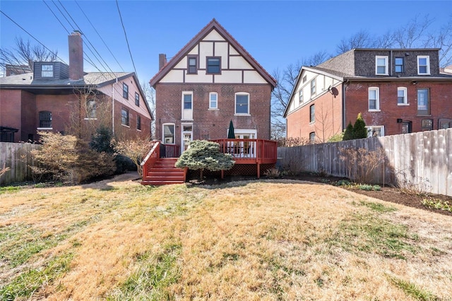 back of house with a yard, brick siding, fence, and a wooden deck