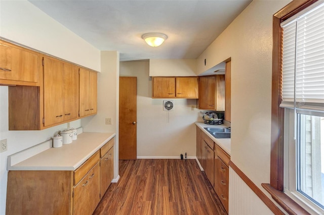 kitchen with brown cabinets, a sink, light countertops, and dark wood finished floors