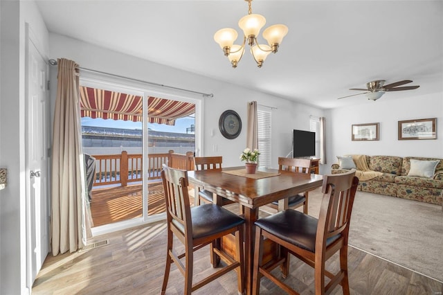 dining area with light wood-style flooring and ceiling fan with notable chandelier