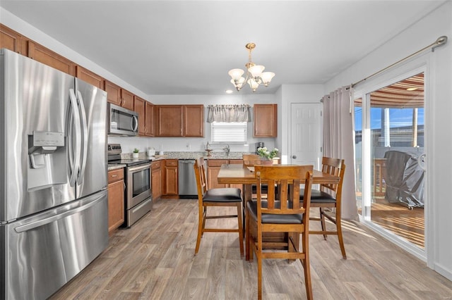 kitchen with a notable chandelier, light countertops, appliances with stainless steel finishes, light wood-type flooring, and brown cabinets