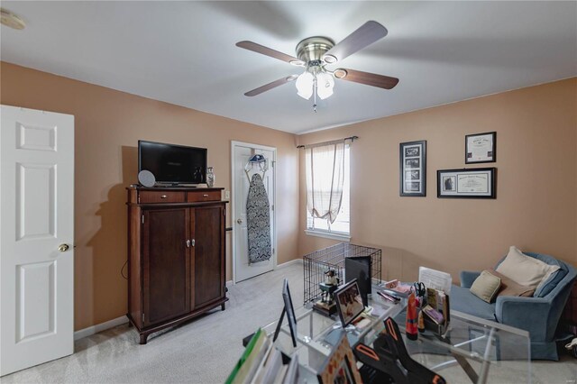 living area featuring light carpet, a ceiling fan, and baseboards