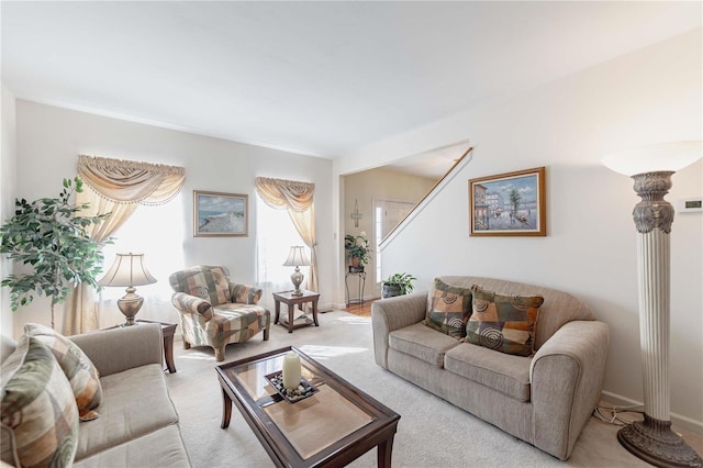 living room featuring light carpet, stairway, and baseboards