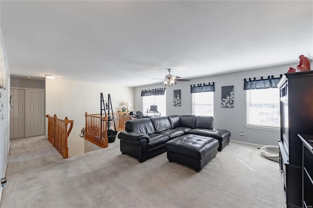 living room featuring ceiling fan, baseboards, and light colored carpet