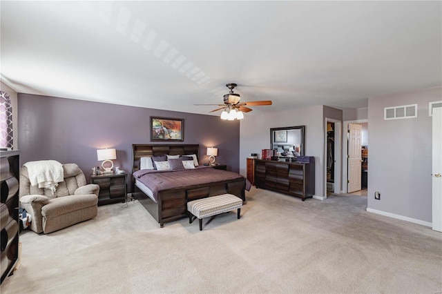 bedroom featuring light carpet, baseboards, visible vents, a ceiling fan, and a walk in closet