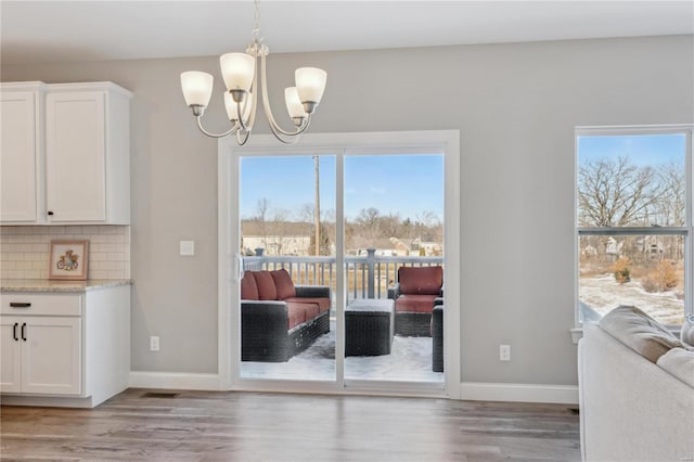 dining space featuring a wealth of natural light, light wood-style flooring, and a notable chandelier