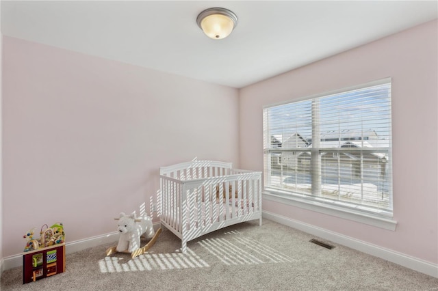 carpeted bedroom with a nursery area, baseboards, and visible vents