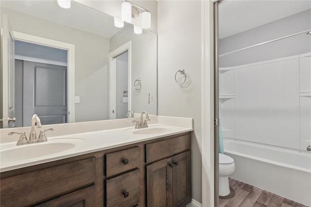 bathroom with double vanity, a sink, wood finished floors, and toilet