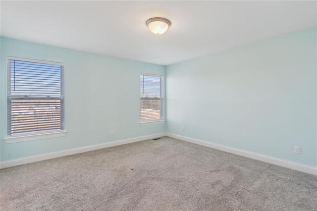 carpeted empty room featuring baseboards and visible vents