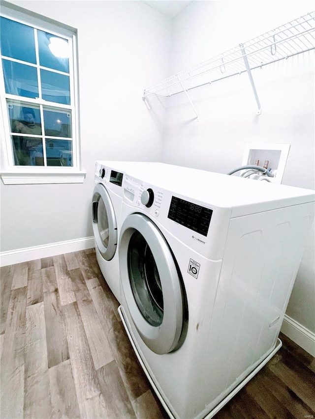 washroom with baseboards, laundry area, washing machine and dryer, and wood finished floors