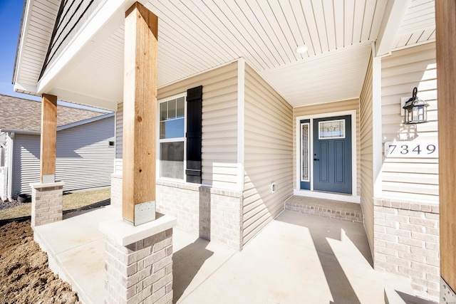 doorway to property with a porch and brick siding