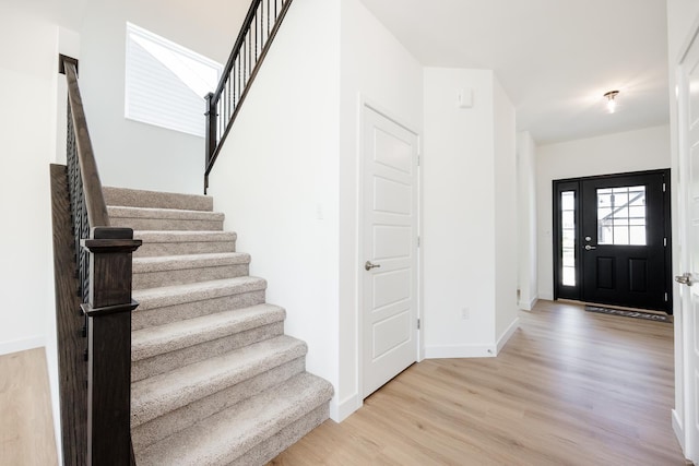 foyer with baseboards, stairway, and light wood-style floors