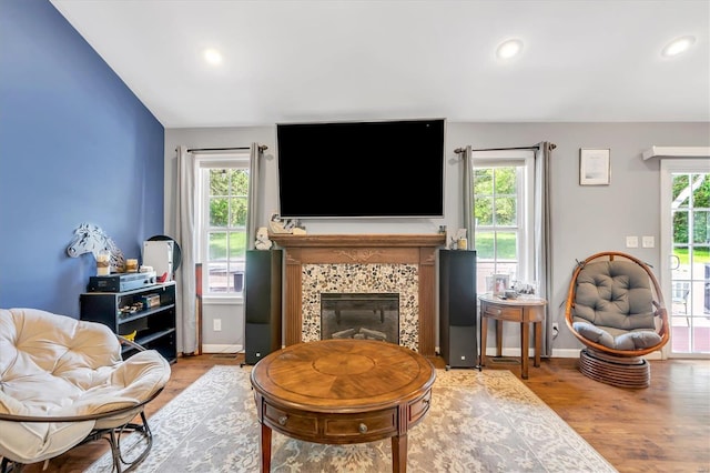 living room featuring a tiled fireplace, wood-type flooring, and plenty of natural light