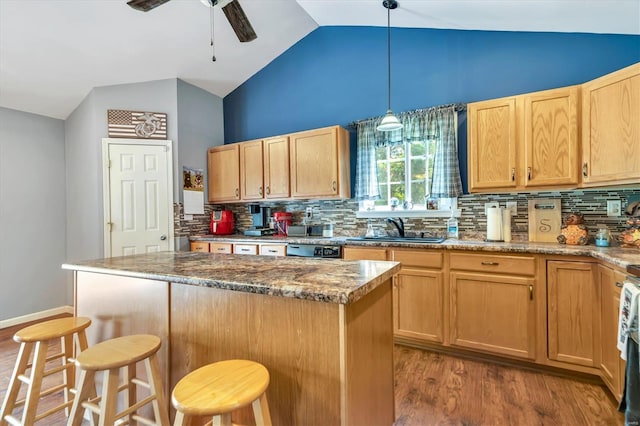 kitchen featuring hanging light fixtures, a breakfast bar area, light stone countertops, and sink