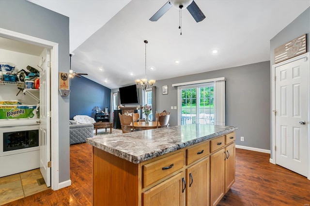 kitchen with ceiling fan with notable chandelier, a center island, and dark wood-type flooring