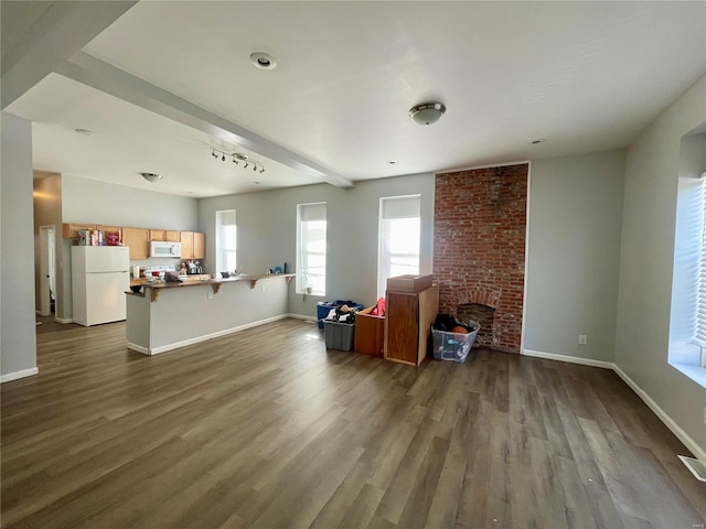 living room featuring beamed ceiling, hardwood / wood-style floors, and a brick fireplace