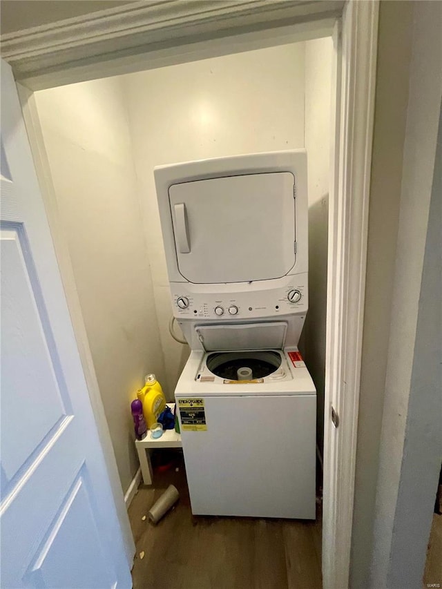 laundry room with stacked washer and clothes dryer and dark hardwood / wood-style flooring