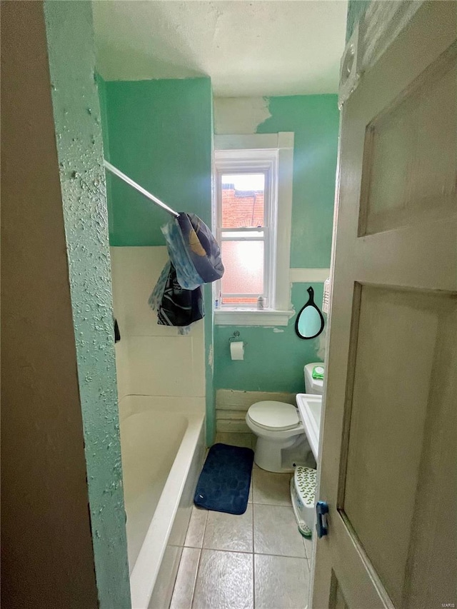 bathroom featuring toilet, tile patterned flooring, and a bathtub