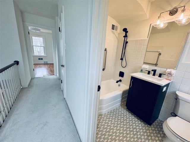 bathroom featuring toilet, visible vents, vanity, tile walls, and washtub / shower combination