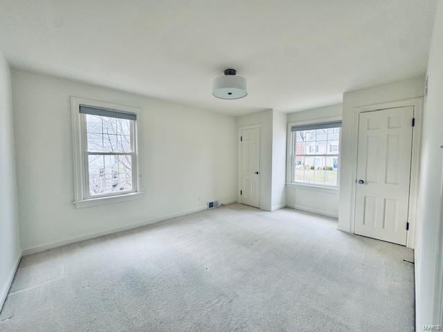 unfurnished room with baseboards and light colored carpet