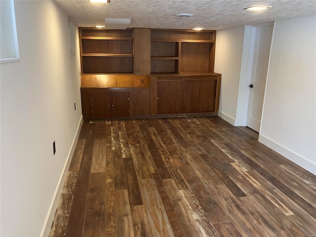 empty room featuring dark wood-style floors, baseboards, and a textured ceiling