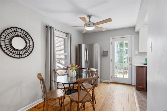 dining space featuring light wood-style flooring, a healthy amount of sunlight, and baseboards