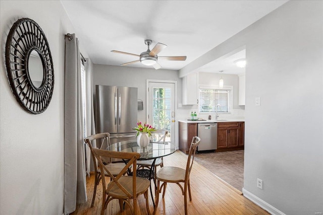 dining area featuring light wood finished floors, baseboards, and ceiling fan