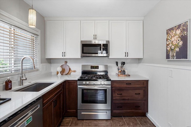 kitchen featuring a sink, hanging light fixtures, light countertops, white cabinets, and stainless steel appliances