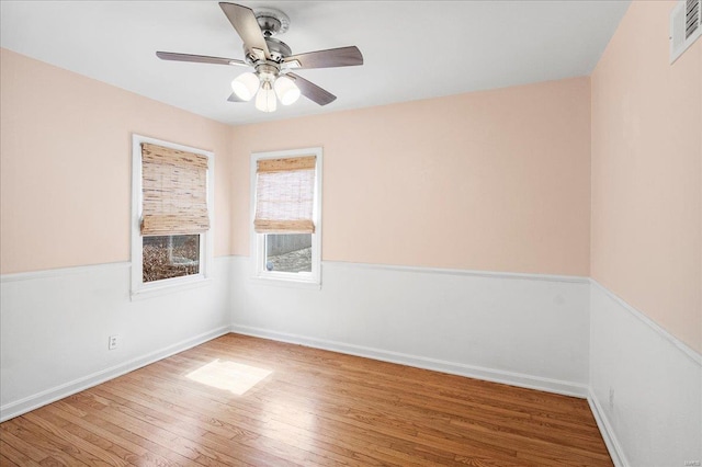 spare room with visible vents, baseboards, wood finished floors, and a ceiling fan