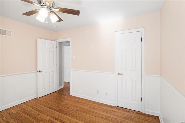 unfurnished bedroom with ceiling fan, wood finished floors, visible vents, and baseboards