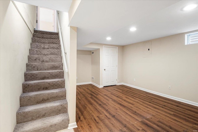 staircase featuring recessed lighting, baseboards, electric panel, and wood finished floors