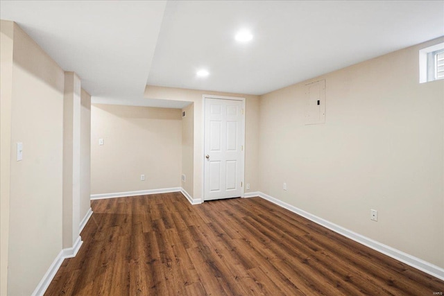 finished below grade area with dark wood-type flooring, electric panel, recessed lighting, and baseboards