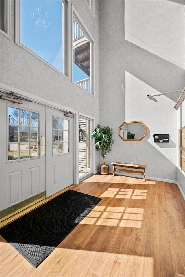 foyer entrance with a towering ceiling, baseboards, wood finished floors, and french doors