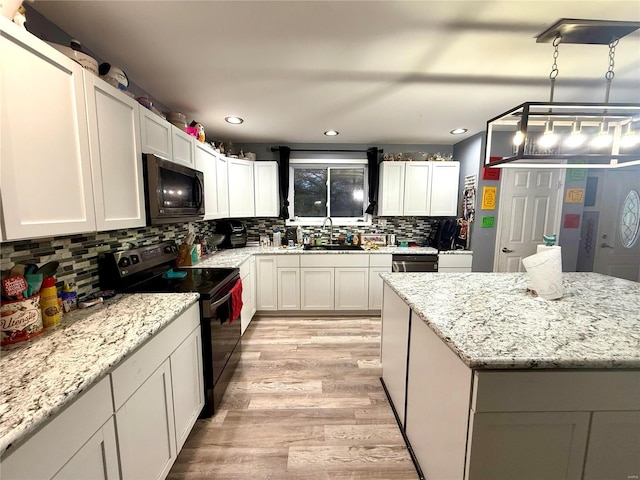 kitchen featuring pendant lighting, sink, white cabinets, light stone counters, and black appliances