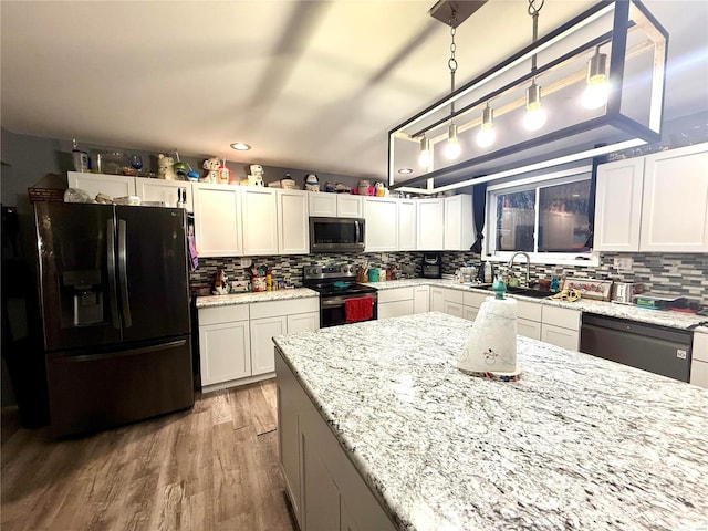 kitchen with white cabinetry, decorative light fixtures, sink, and black appliances