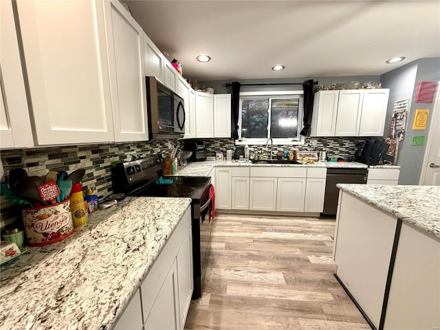 kitchen featuring sink, light hardwood / wood-style flooring, white cabinetry, black appliances, and decorative backsplash