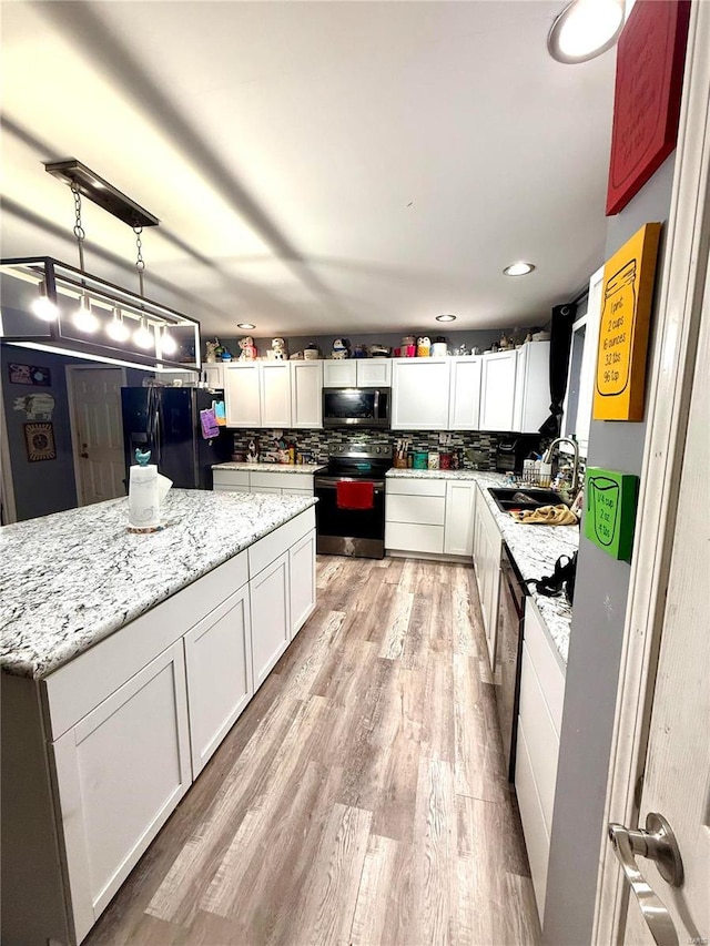 kitchen featuring appliances with stainless steel finishes, sink, white cabinets, and decorative light fixtures