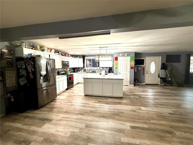 kitchen featuring light hardwood / wood-style flooring, a kitchen island, pendant lighting, stainless steel appliances, and white cabinets