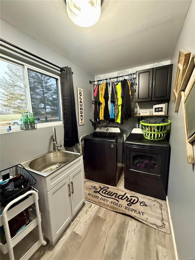 washroom featuring cabinets, sink, light hardwood / wood-style floors, and washing machine and dryer